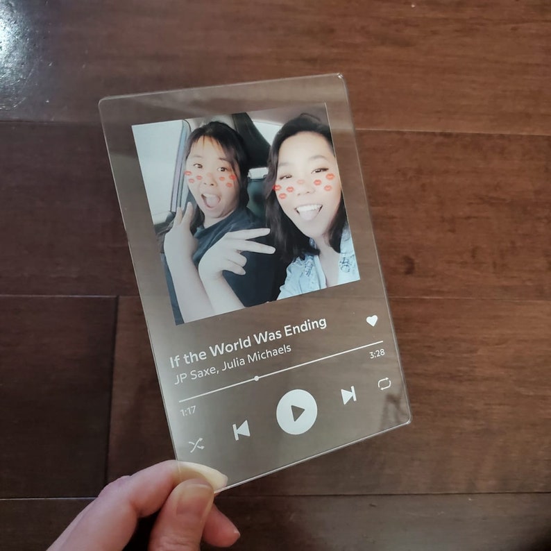 May include: A clear acrylic photo frame featuring a picture of two people in a car. The frame is designed to resemble a music player screen, with the song title "If the World Was Ending" by JP Saxe and Julia Michaels shown below the photo.
