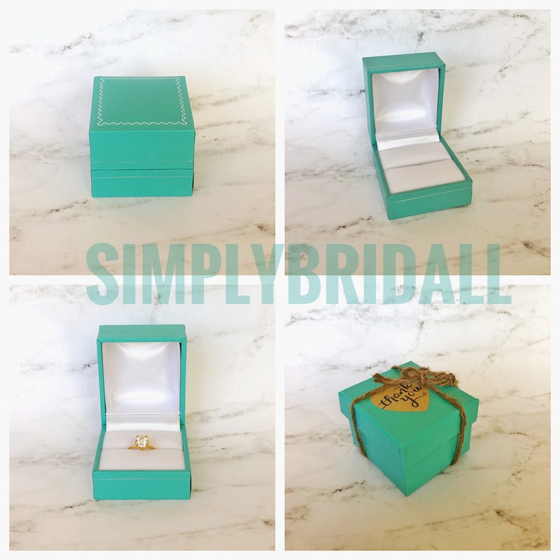 May include: Four turquoise ring boxes, two are open and two are closed. One box has a ring inside and another box has a "Thank You" tag on it.