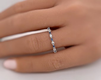 May include: A silver band ring with alternating round and rectangular blue sapphires and small round diamonds.