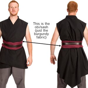 May include: A black sleeveless tunic with a burgundy obi/sash tied around the waist. The sash is made of a soft, flowing fabric.