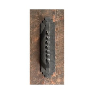 May include: Black metal door handle with a twisted design. The handle is mounted on a wooden surface.