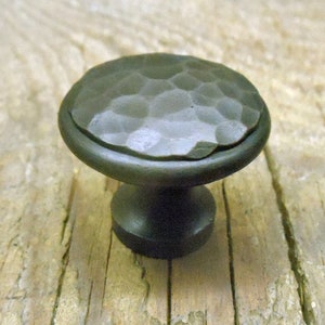 May include: A dark green hammered metal cabinet knob with a round top and a short, round base.
