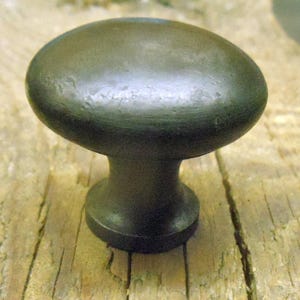 May include: A black metal cabinet knob with a rounded top and a smooth, slightly textured surface.