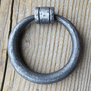 May include: A silver metal ring pull handle with a textured finish. The handle is round and has a slightly curved shape.
