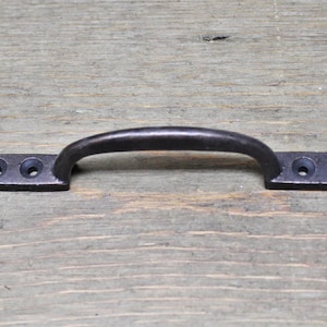 May include: Black metal cabinet pull with a rounded handle and two holes on each side.