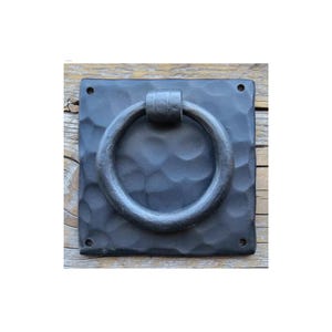May include: Black metal door knocker with a hammered square plate and a round ring handle.
