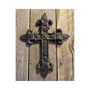 May include: A black metal cross with a fleur-de-lis design. The cross is mounted on a rustic wooden background.