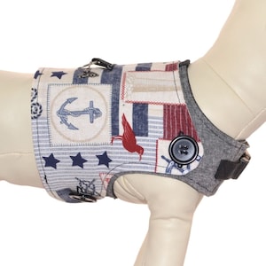 Puede incluir: Un arnés para perro azul y rojo con temática náutica. El arnés presenta un ancla, estrellas y rayas. El arnés se muestra en un maniquí de perro blanco. Se incluye una tabla de tallas en la imagen. "Pawzly Harness Fitting Chart" está impreso en la tabla. "It's a doggy thing Pawzly.com" está impreso en un círculo azul con una ilustración de perro blanco.