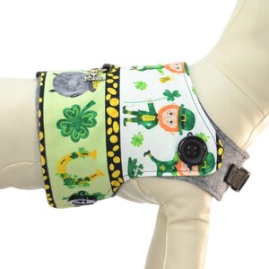 May include: A green, yellow, and white dog harness with a shamrock and leprechaun design. The harness is shown on a white mannequin dog. A size chart is included with neck, chest, and weight measurements in inches and pounds.