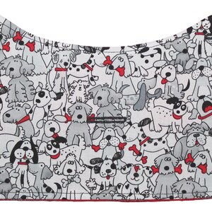 Puede incluir: Tela blanca con un patr&oacute;n de perros negros y grises que llevan collares rojos. La tela tiene la forma de un collar de perro.