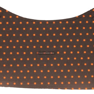May include: A black fabric with orange polka dots. The fabric has a curved shape and is sewn together at the edges.