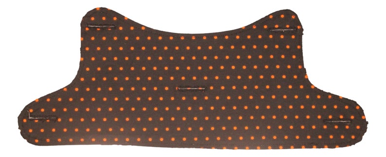 May include: A black fabric with orange polka dots. The fabric has a curved shape and is sewn together at the edges.