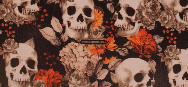 May include: A black fabric with a repeating pattern of white skulls and orange flowers. The skulls have a detailed design and are surrounded by leaves and vines.