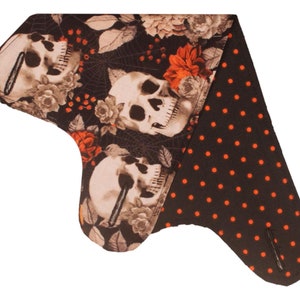 May include: A black and orange fabric bandana with a skull and floral print on one side and a black and orange polka dot print on the other side.