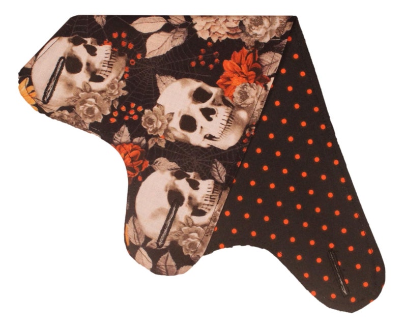 May include: A black and orange fabric bandana with a skull and floral print on one side and a black and orange polka dot print on the other side.
