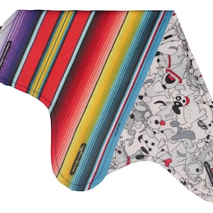 Puede incluir: Un pa&ntilde;uelo triangular con un patr&oacute;n de rayas coloridas en un lado y un lado blanco con un patr&oacute;n de perro blanco y negro. El pa&ntilde;uelo est&aacute; hecho de tela y tiene un borde cosido.