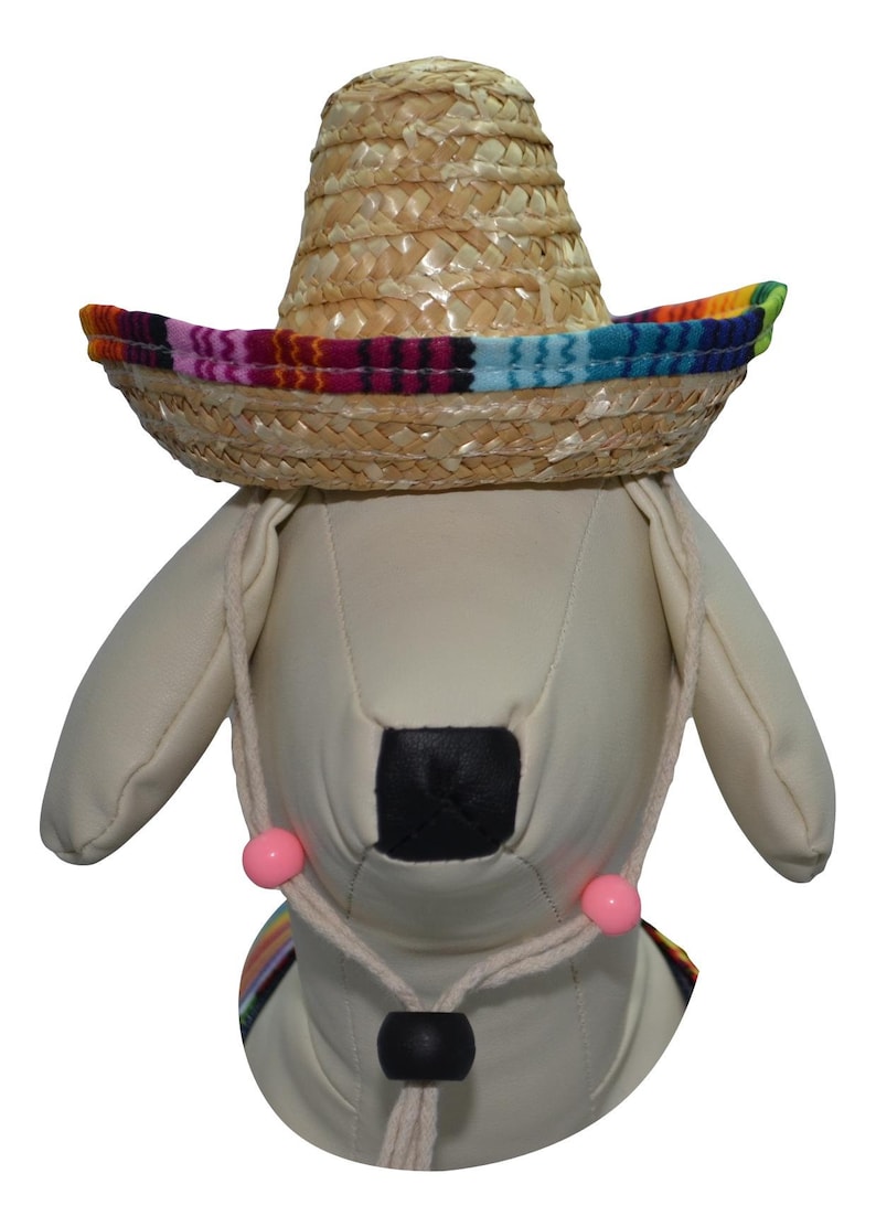 May include: A white stuffed dog wearing a straw sombrero with a colorful band. The sombrero has a pink and white string tied around the dog's neck with pink beads.