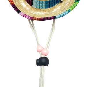 May include: A colorful straw sombrero with a chin strap and pink beads. The hat has a woven straw crown and a multi-colored band.