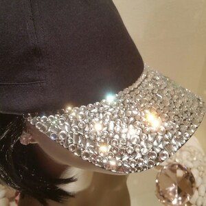 May include: A black baseball cap with a visor covered in clear rhinestones.