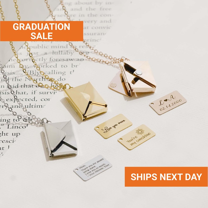 May include: Gold and silver envelope pendant necklaces with engraved tags. The tags read "Love you more", "You're my sunshine", and personalized messages. The image also includes the text "GRADUATION SALE".