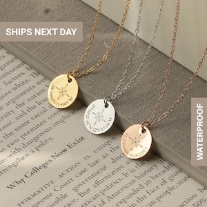 Puede incluir: Tres delicados collares con colgantes de rosa de los vientos en oro, plata y oro rosa. Cada colgante presenta coordenadas y un diseño de brújula. Los collares se muestran en una página de libro.