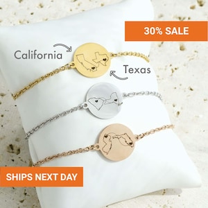 May include: Three chain bracelets with circular pendants, each engraved with two US state outlines connected by a dotted line and small hearts. The top bracelet is gold, the middle is silver, and the bottom is rose gold, all featuring state maps.