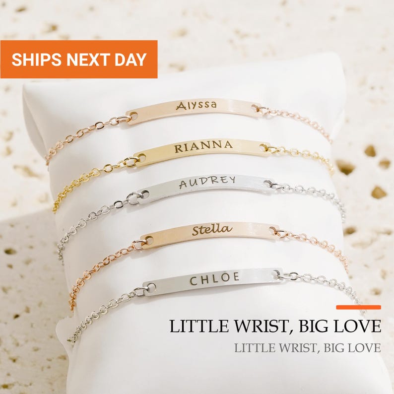 May include: Five delicate metal chain bracelets with horizontal rectangular bars, each engraved with a unique name: Alyssa, Rianna, Audrey, Stella, and Chloe. The bracelets feature varying metallic finishes including gold, silver, and rose gold tones.