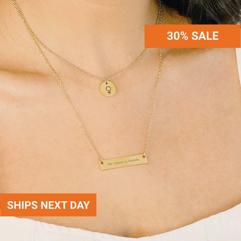 a close-up of a person's neck with a gold necklace and a small pendant. The pendant has a symbol on it, and there is a rectangular charm hanging from the necklace. The image also includes text that says "30% SALE" and "SHIPS NEXT DAY".