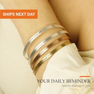 May include: A set of four thin metal cuff bracelets in silver, gold, and rose gold tones. Each bracelet features engraved text including the phrases NEVER GIVE UP, STRONGER than the storms, faith over FEAR, and Do What Makes Your Soul SHINE.