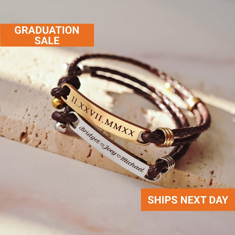 May include: Two personalised leather bracelets with metal nameplates. One is gold-toned with Roman numerals, the other is silver-toned with names. The bracelets are brown and have a braided design. The image includes the text "GRADUATION SALE".