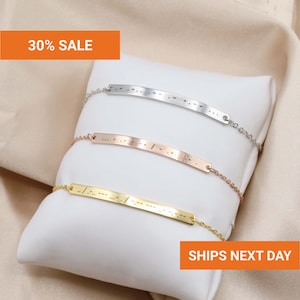 May include: Three delicate chain bracelets featuring thin, curved metal bars engraved with Morse code patterns. The set includes one silver-toned, one rose gold-toned, and one gold-toned bracelet, each secured with a fine link chain.