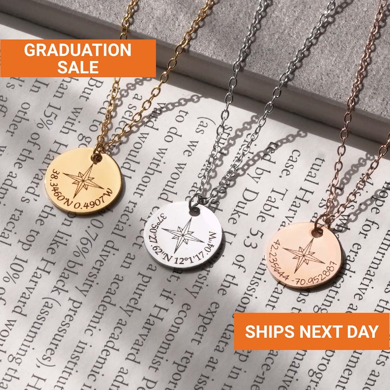 Puede incluir: Tres collares con colgantes de br&uacute;jula en oro, plata y oro rosa. Cada colgante presenta un dise&ntilde;o de br&uacute;jula y coordenadas. La imagen incluye el texto "GRADUATION SALE" y "SHIPS NEXT DAY".