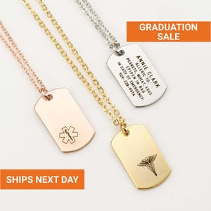May include: Three metal dog tag necklaces in rose gold, gold, and silver. The tags have different symbols and text, including a medical symbol and the text "GRADUATION SALE". One tag reads "Annie Clark" and allergy information.