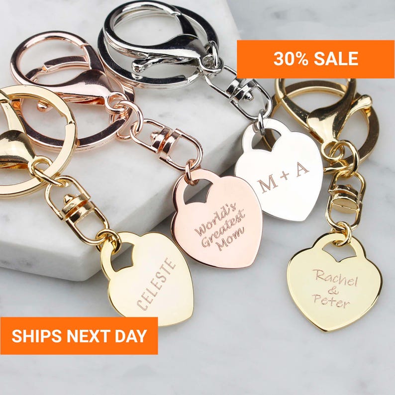 a collection of personalized keychains with engraved names on them, arranged on a marble surface.
