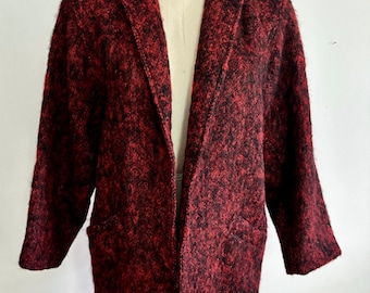 May include: A red and black fuzzy knit blazer with a long sleeve and a collar. The blazer has two pockets on the front.