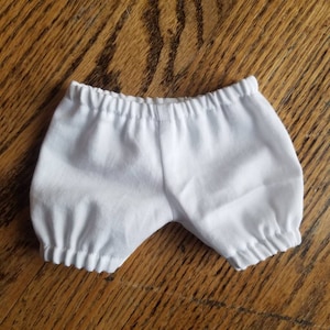 May include: White cotton baby bloomers with elastic waistband.