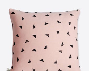 May include: A pink throw pillow with a black triangle pattern. The pillow has a "tiny day" label in the bottom left corner.