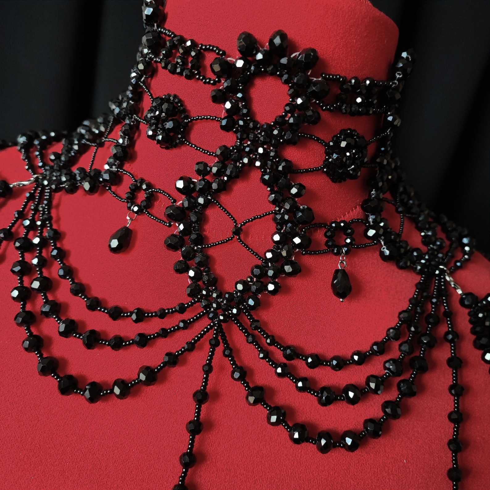 Close-up of gothic black shoulder necklace with layered bead chains and floral choker details.