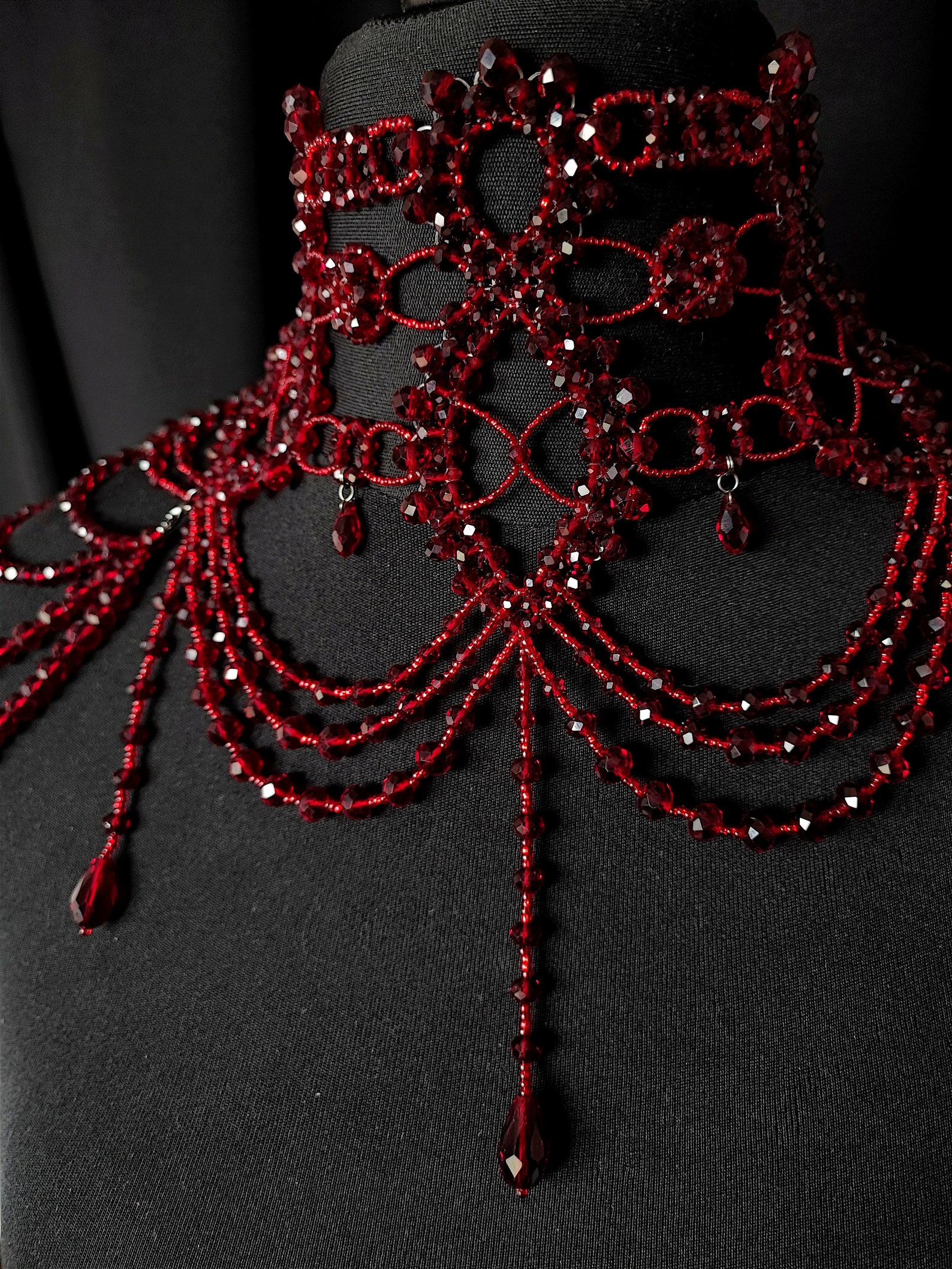 Close-up of burgundy shoulder choker necklace with dangling crystal strands and ornate detailing.