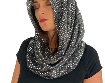 May include: A hooded cowl scarf featuring a black fabric base covered in small, reflective silver sequins. The accessory drapes around the neck and extends over the head as a hood, creating a shimmering, textured appearance with a metallic finish.