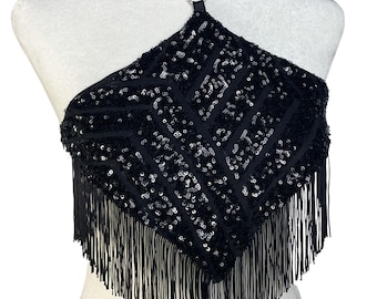 May include: A black halter top featuring a diamond-shaped front panel covered in dense, shimmering sequins arranged in a geometric pattern. The garment includes a thin black neck strap attached to a silver ring and long black fringe trim.