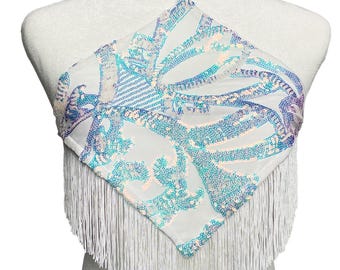 May include: A white halter top featuring a diamond-shaped front panel covered in iridescent blue and silver sequins. The garment includes a thin white neck strap attached with a silver metal ring and is finished with long white fringe trim.