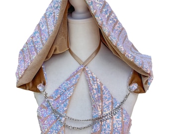 May include: A sequined festival top and hooded cape set. The top is a halter style with a chain detail and beaded fringe. The hood and top are covered in iridescent sequins. The hood is lined with a tan velvet material.