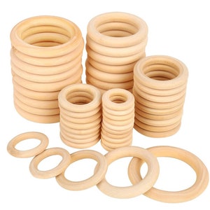 May include: Several stacks of unfinished wooden rings in different sizes. The natural wood colour is visible, with the rings appearing smooth and ready for crafting. The rings are arranged on a white background. Measurements are not available.