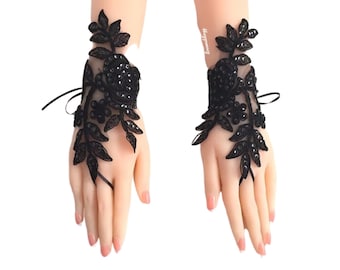 May include: A pair of black lace fingerless gloves with floral embellishments and black beading.