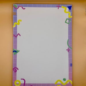 May include: A white notepad with a purple, blue, green, and yellow geometric border. The border has a grid pattern.