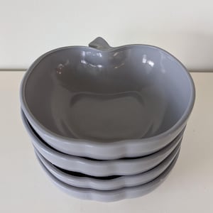 May include: Set of four gray ceramic bowls shaped like apples. The bowls are stacked on top of each other.