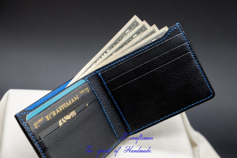 May include: A black leather wallet with blue stitching, open to reveal cash and a credit card with the text "X CRAFTSMAN".