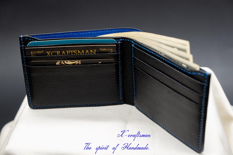May include: A black leather wallet with blue stitching, open to reveal multiple card slots and a cash compartment. The wallet has a gold embossed logo that reads "X-craftsman".
