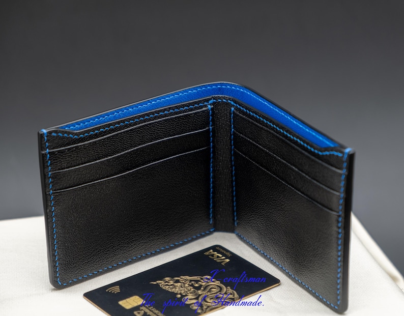 May include: Black leather wallet with blue stitching and multiple card slots. The wallet is open and a credit card is visible inside.